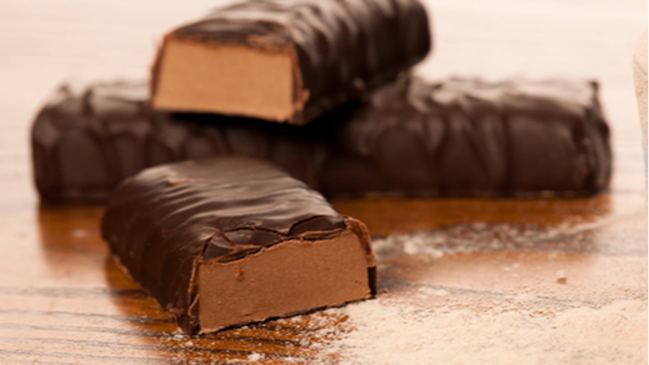 Whey protein powder and chocolate protein bar on wooden background