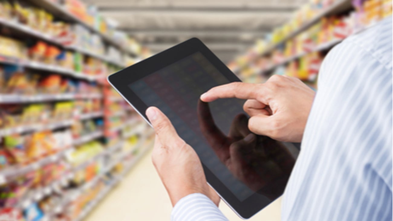 Businessman checking inventory in minimart on touchscreen tablet