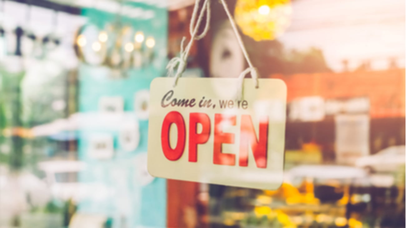 Open sign broad through the glass of door of a store. Vintage tone filter color style.