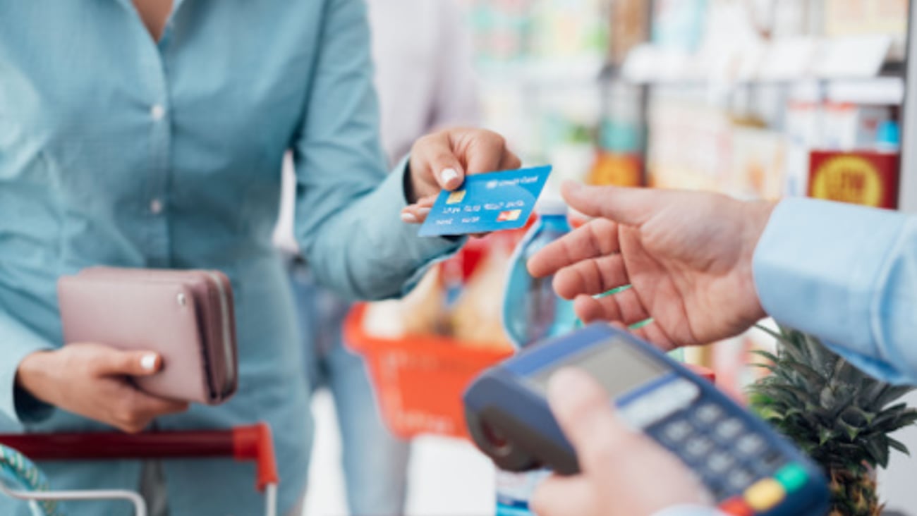 Woman at the supermarket checkout, she is paying using a credit card, shopping and retail concept