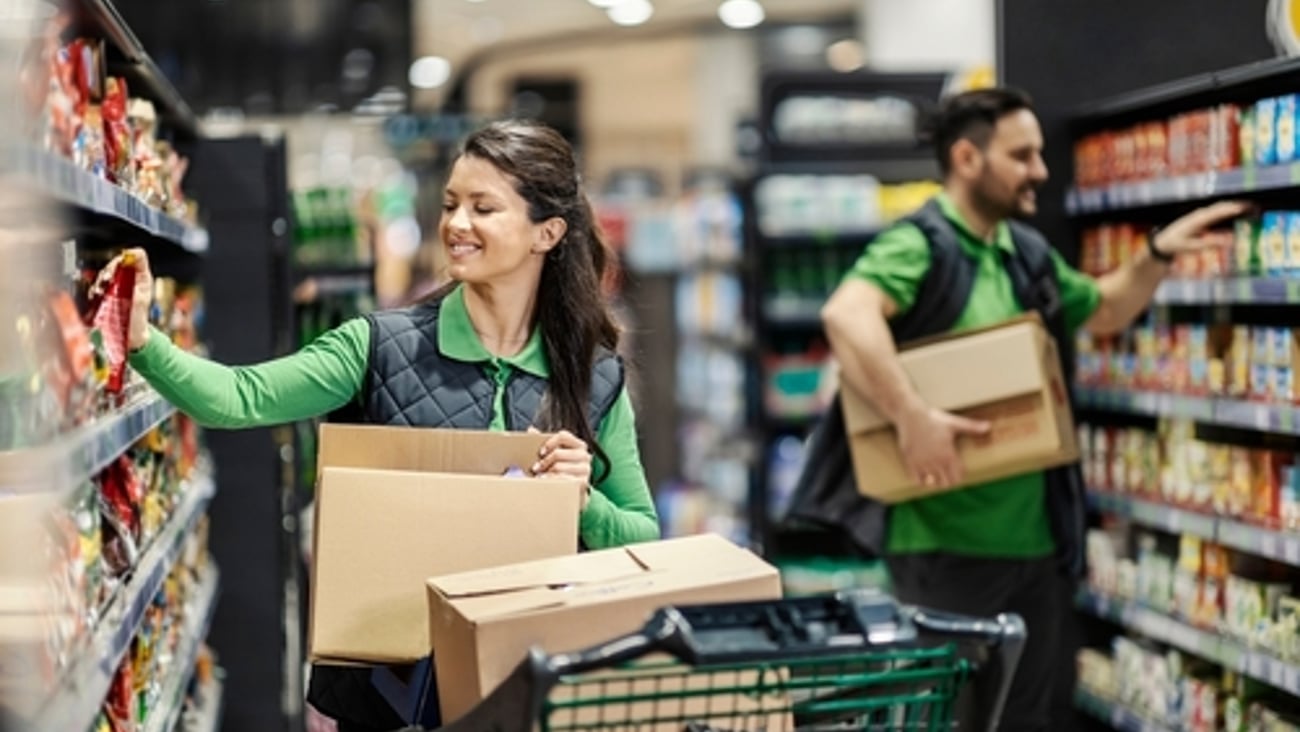 Happy employees putting products on shelves in supermarket.
