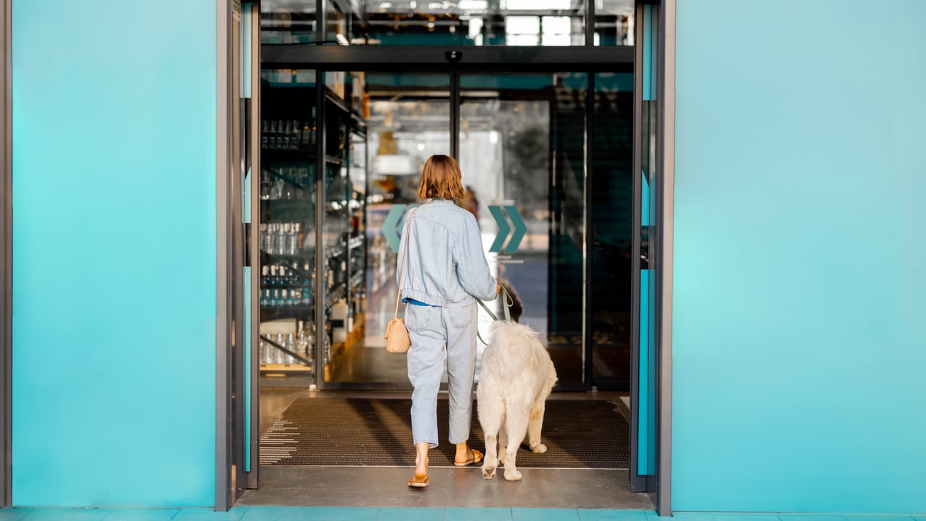 dog with woman walking into store