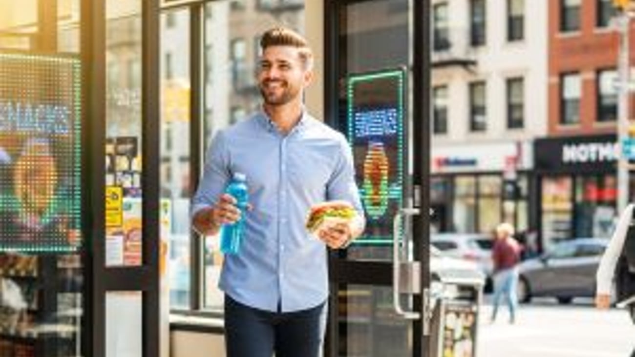 Man with food exiting a convenience store stock image teaser