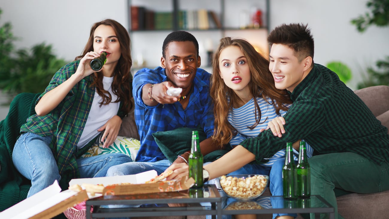 group reacting while watching tv and eating and drinking, at a watch party