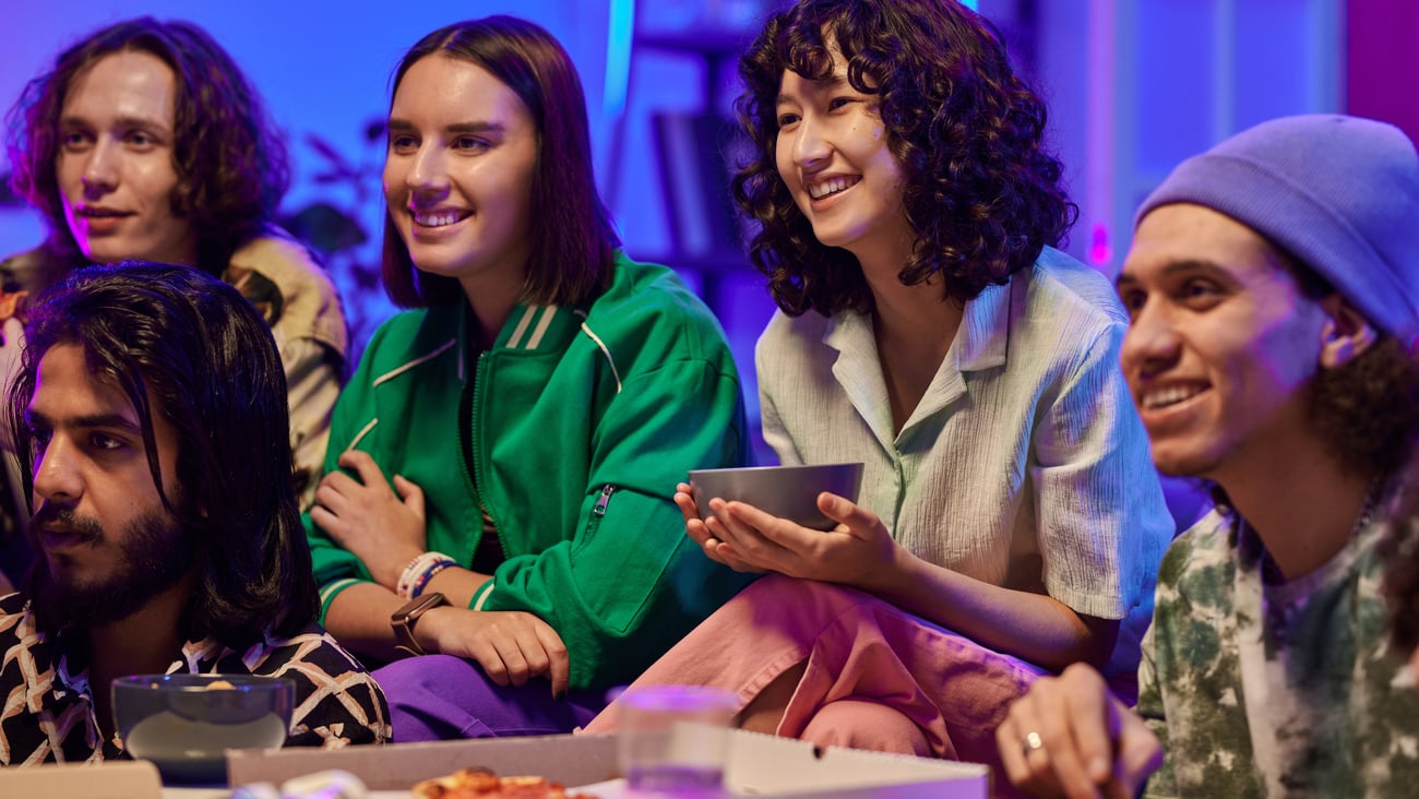 group of people snacking and eating pizza and watching TV