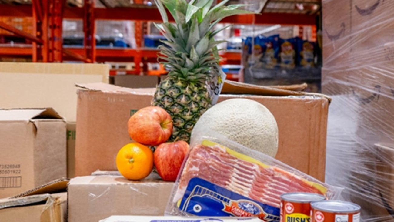 Food donations for Mississauga food bank: Pineapple, eggs, bacon and can of beans on top of cardboard boxes.
