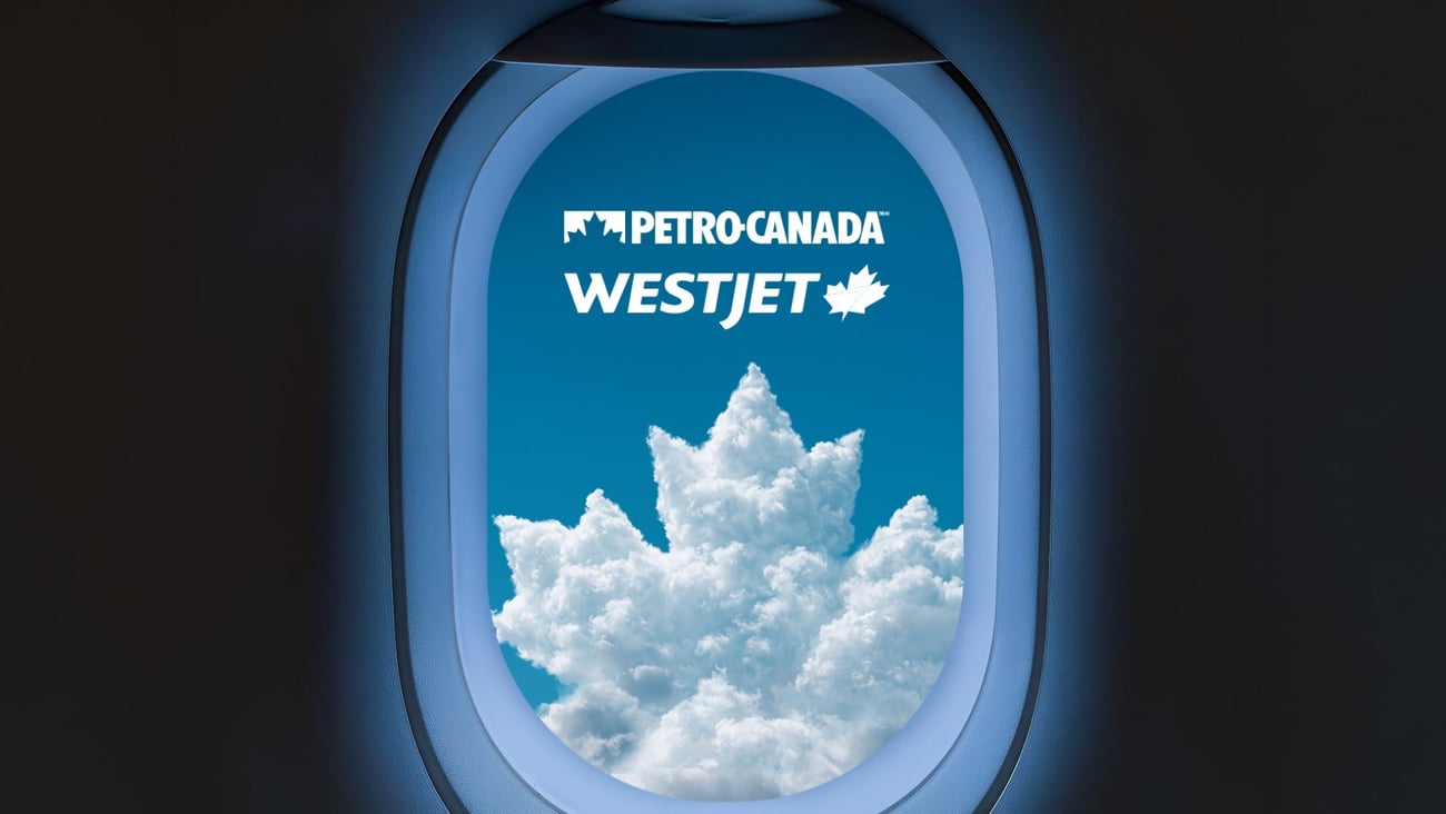 View out of an airplane window focused on a cloud shaped like Petro Canada logo below WestJet logo