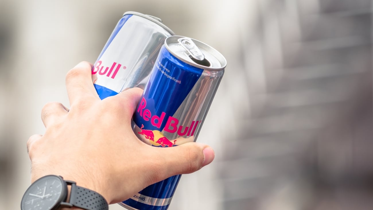 hand holding two cans of Red Bull