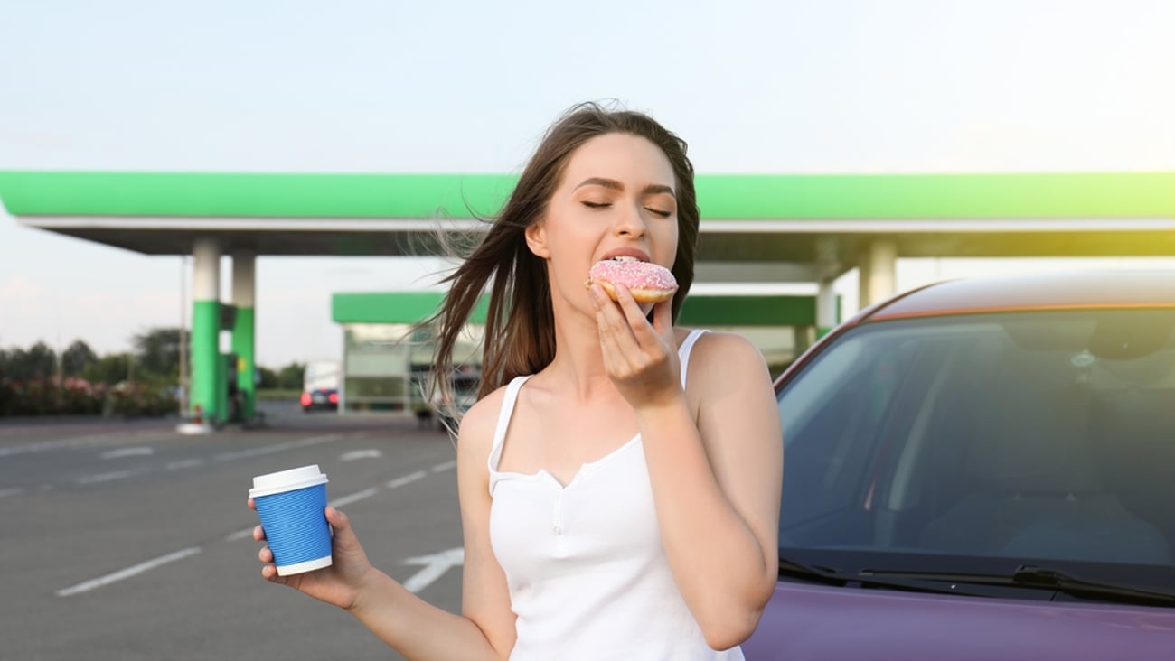 woman eating food in a gas station forecourt