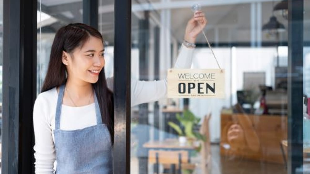 Employee placing Open sign on door