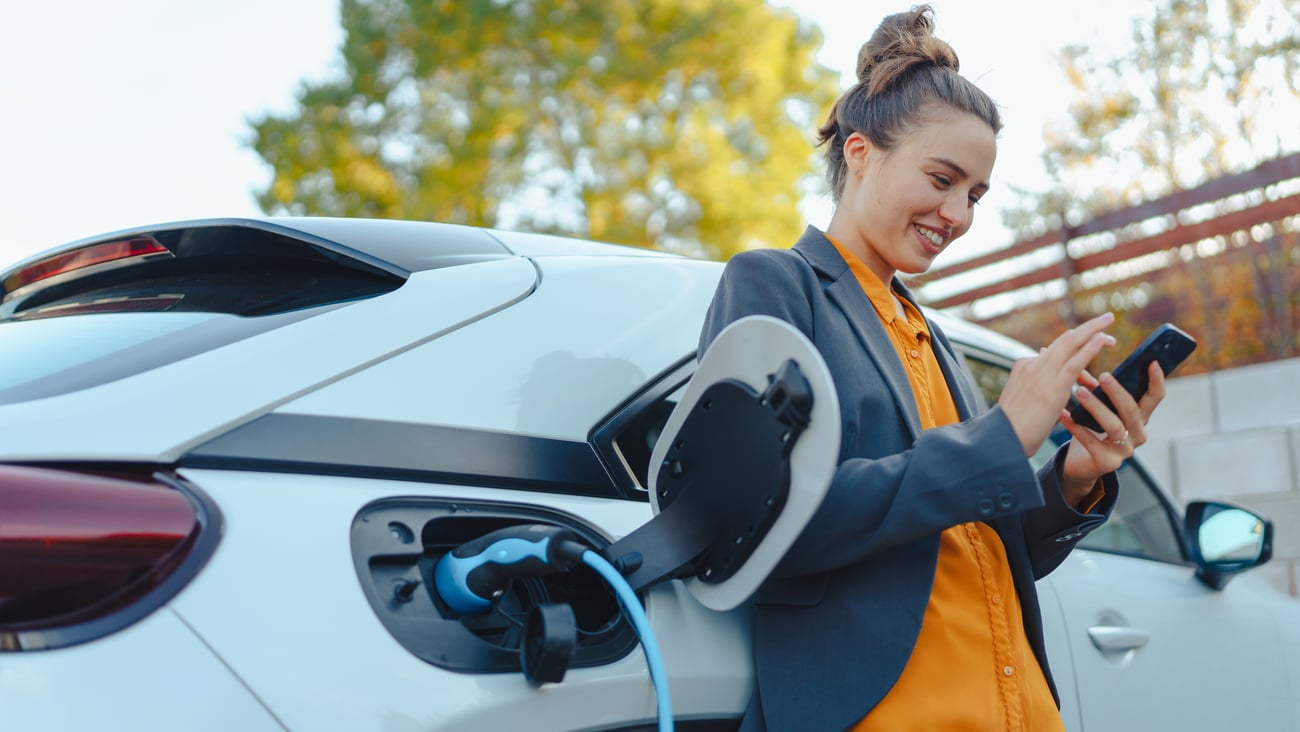 Young women with smartphone charging vehicle