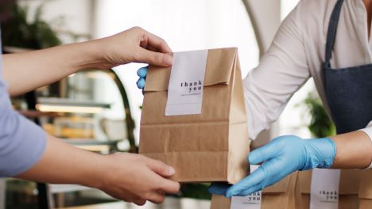 Store employee passing a bag of food to a customer