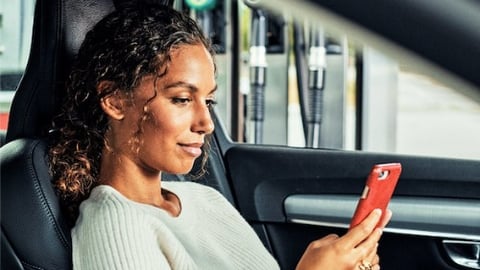 Woman in car, paying with her mobile phone