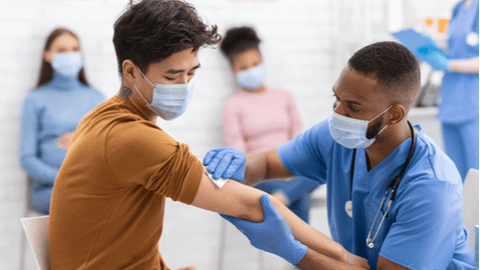 man getting vaccine while others look on