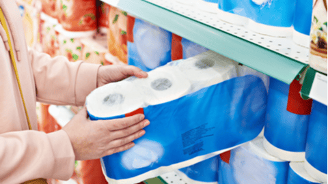 Woman pulling toilet paper off store shelf