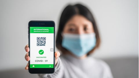 woman holding phone with vaccine QR code