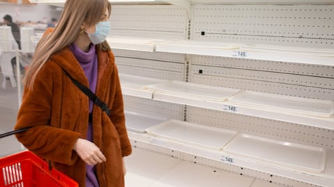 Young woman in medical mask and empty shelves in supermarket