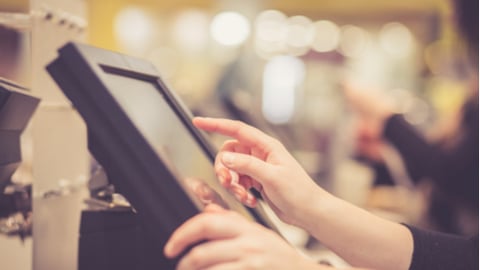 Young woman hands counting / entering discount / sale to a touchscreen cash register, market / shop (color toned image)