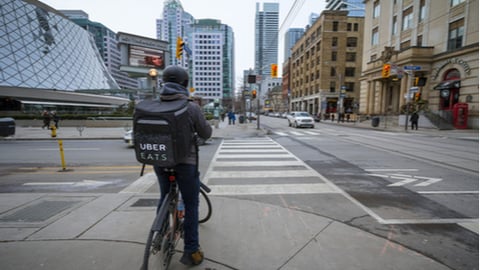 Uber Eats delivery man on a bicycle waiting to cross a street