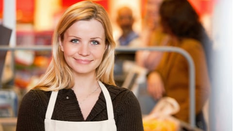 Closeup of a young shop assistant with customer in the background