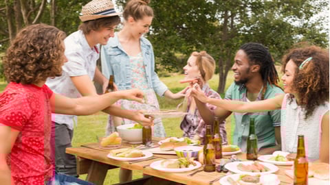 Happy friends in the park having lunch on a sunny day