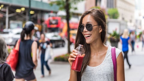 Urban city lifestyle hipster asian woman drinking healthy fruit vegetable berry juice smoothie walking on downtown street