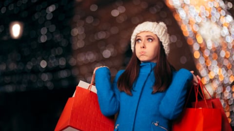 Tired Girl Holding Shopping Bags on Christmas Lights Decor. Exhausted stressed holidays buyer feeling fatigued