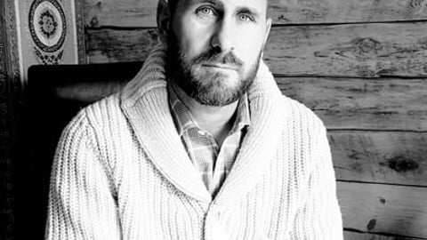 Sean Sportun in a knit cable sweater, with beard, looking into the camera - black and white shot