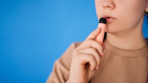  random pretty woman standing and about to hover on a blue background in the studio. the concept of vaping and modern smoking.