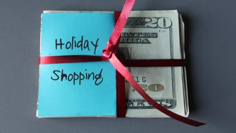 stack of american cash with a bow on it, sticky note that reads holiday shopping