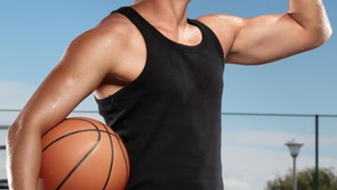 Young man drinking mineral water on a basketball court