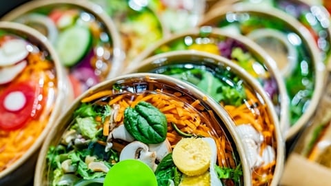 Pre-packaged vegetable salads displayed in a commercial refrigerator