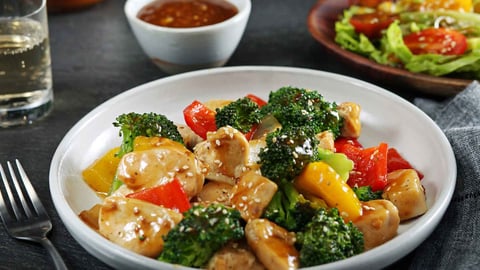 Sesame stirfry plated with chicken and broccoli on nicely set table