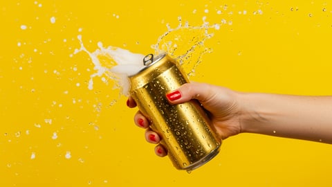 Open and foaming can in a woman's hand