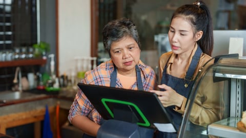 Two women working together at till at coffee or other shop