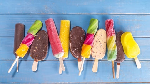 Assorted popsicles and chocolate-covered ice cream on a stick, on a blue painted wooden background 