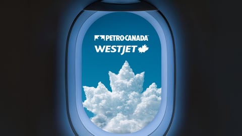 View out of an airplane window focused on a cloud shaped like Petro Canada logo below WestJet logo