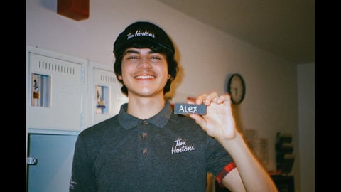 Unnamed youth in Tim Hortons uniform holds up his name tag