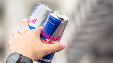 hand holding two cans of Red Bull