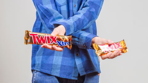 man holding two bars of Twix