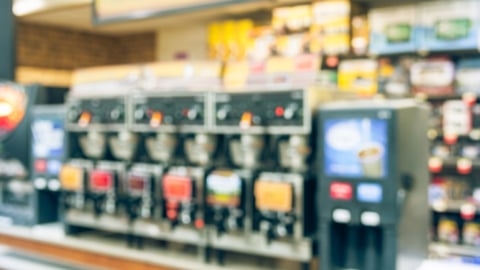 Blurred modern convenience store gas station . Variety items on display such as impulse snack, energy drink, coffee, hot food, tobacco, cigarette, clothes, lottery ticket. 