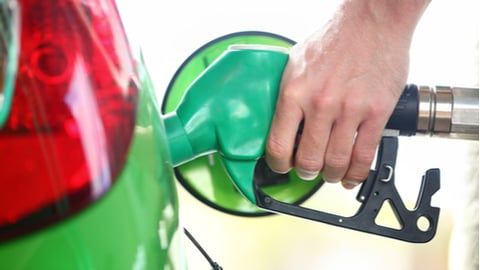 Gas station pump. Man filling gasoline fuel in green car holding nozzle. Close up.