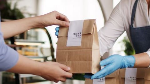 Store employee passing a bag of food to a customer