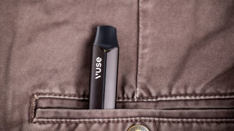 Electronic cigarette Vuse on brown jeans.