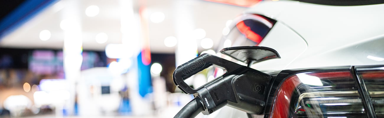 gas pump in EV car, station in the background