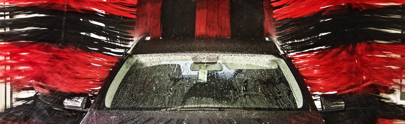 Black car in car wash with red and black brushes