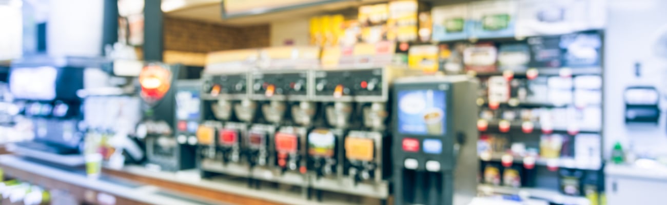 Blurred modern convenience store gas station . Variety items on display such as impulse snack, energy drink, coffee, hot food, tobacco, cigarette, clothes, lottery ticket. 