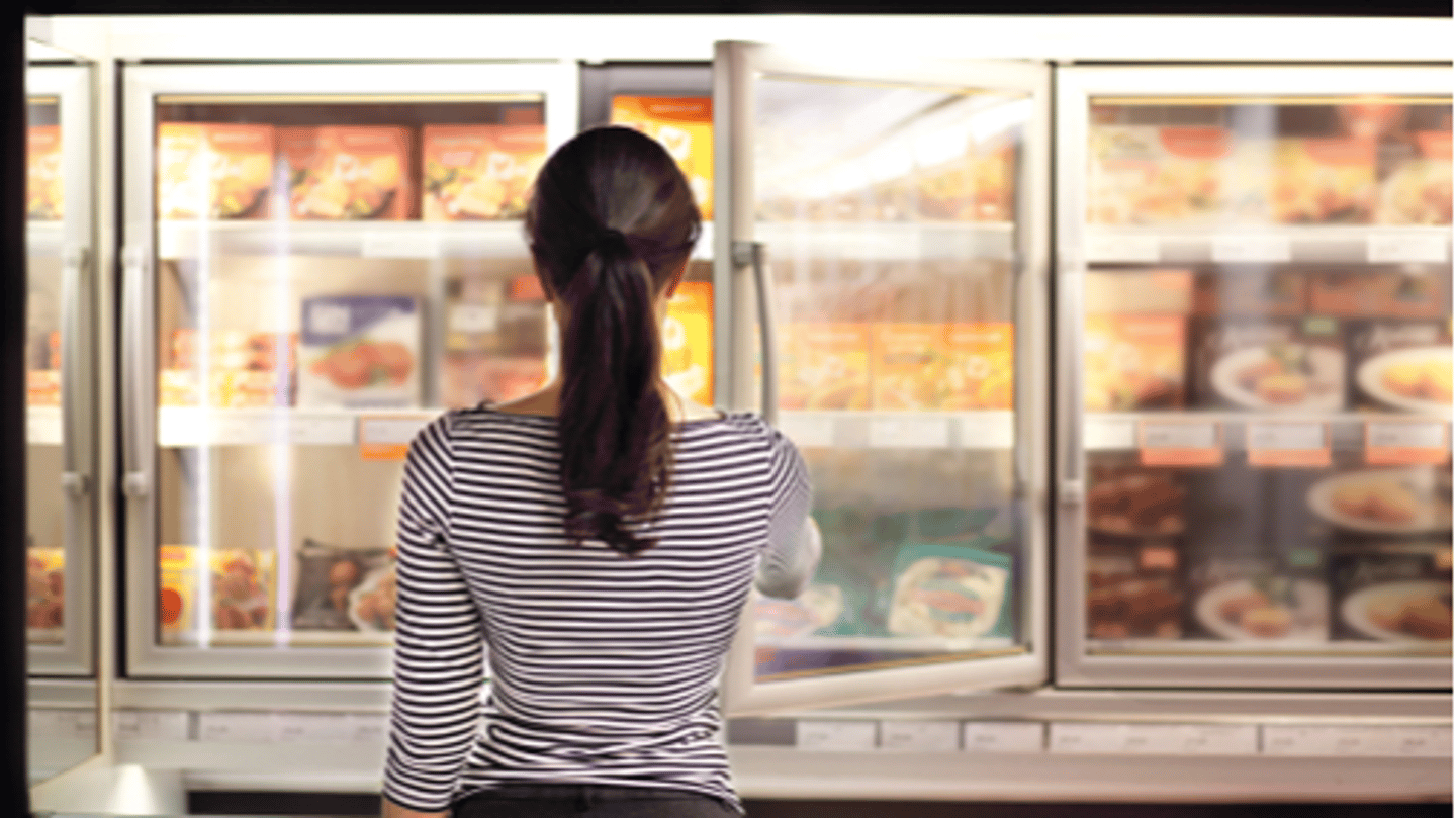 woman reaching into freezer in store