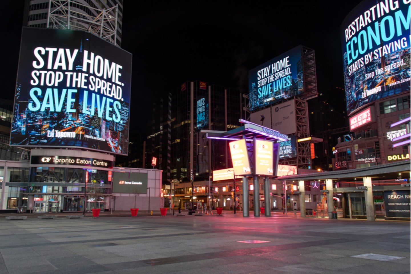 TORONTO, CANADA - May 12, 2020: Toronto’s Young-Dundas Square empty at empty, with digital billboards reading “Stay home. Stop the spread. Save lives.” during the COVID-19 pandemic.