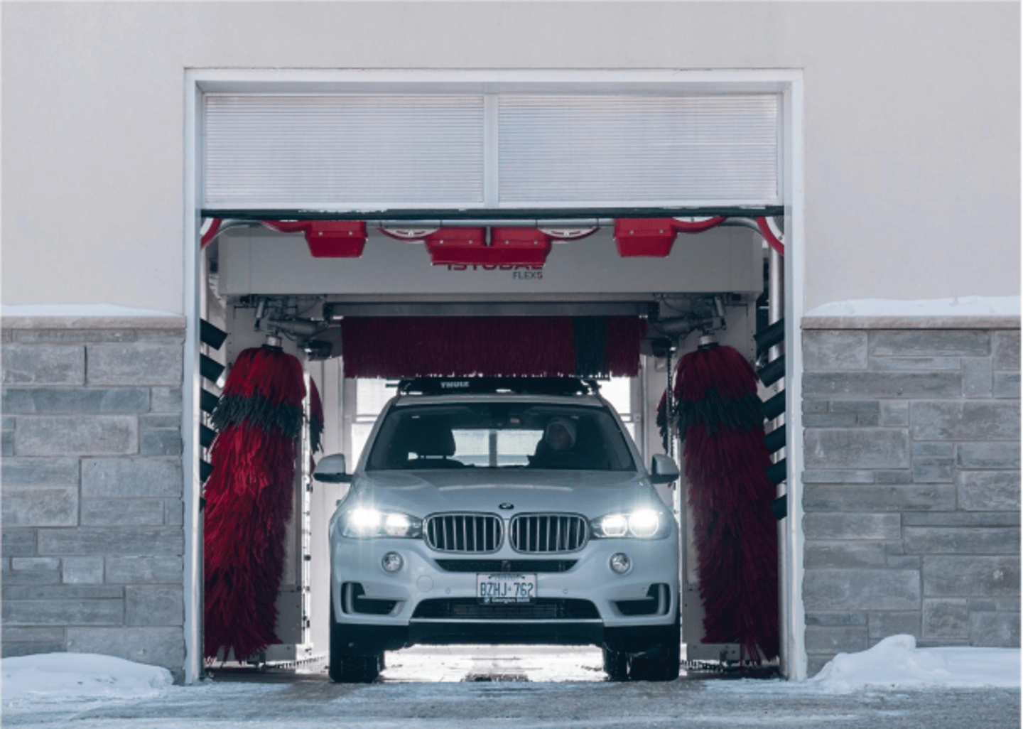 white BMW exiting via car wash door in the winter 